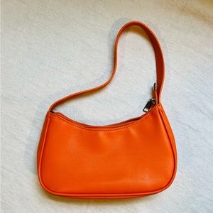 Small orange handbag with silver zipper accent.